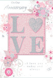 This anniversary card offers a gentle celebration of enduring love, akin to a pastel bouquet arranged in a Seven Sisters flat overlooking leafy back gardens. At its core, the word LOVE rises from the card in soft, raised glitter, each letter clearly defined yet tender in its shaping. The letter O is transformed into a shimmering heart, textured in silver so it sparkles with every tilt, much like light catching on a polished vase on a windowsill near Tottenham Green. Around this central motif, delicate blossoms in blush pink, mauve, and pale ivory unfold in soft, painterly strokes, as though they were brushed on with watercolour. Their petals overlap lightly, with fine outlining and subtle shading that suggest layers and depth, while slender stems and flowing lines curl outward, evoking vines or dancing ribbons of foliage. Tiny flourishes-scattered petals, looping swirls, and graceful butterfly-like shapes-add motion and a playful note, reminiscent of petals caught on a breeze along West Green Road. The background blends pastel pink and silvery grey in a gentle gradient, creating a calm, intimate atmosphere that keeps the focus on the central heart and surrounding flowers. The phrases On Our Anniversary and I love you today and always are rendered in an understated, elegant script, their curves echoing the sweeps of the floral lines. The overall impression is of a keepsake meant to be treasured, like a pressed flower saved between pages: soft, romantic, and deeply personal, perfectly suited to marking another year of shared stories and steadfast devotion.